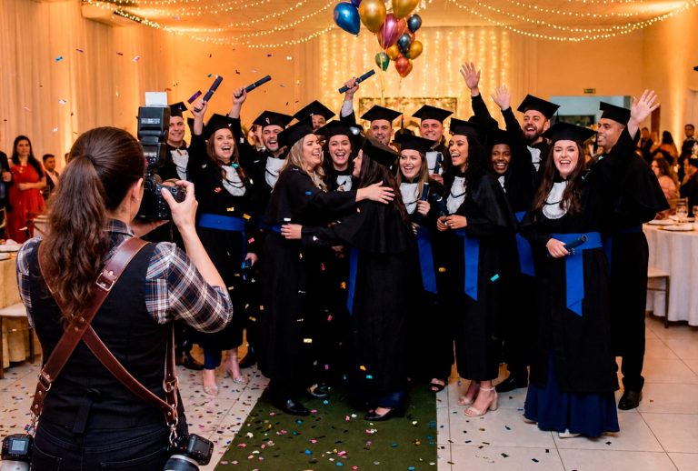 Fotógrafa registrando a celebração de uma turma durante cerimônia de formatura.
